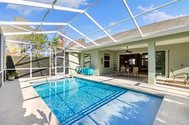 view of swimming pool with a patio area, ceiling fan, and glass enclosure