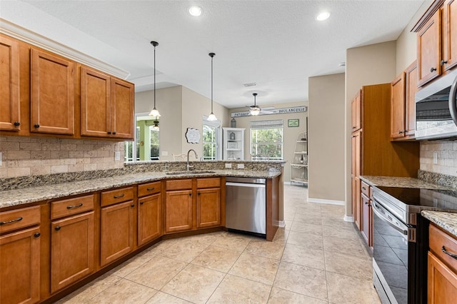 kitchen featuring sink, light stone counters, pendant lighting, stainless steel appliances, and decorative backsplash