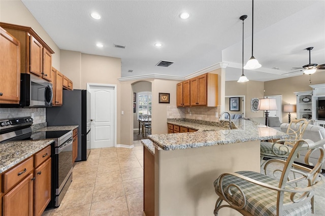 kitchen featuring a breakfast bar, sink, hanging light fixtures, kitchen peninsula, and stainless steel appliances