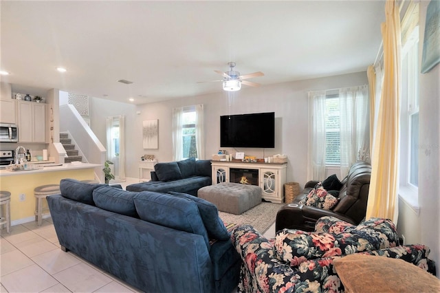 tiled living room with a healthy amount of sunlight, sink, and ceiling fan