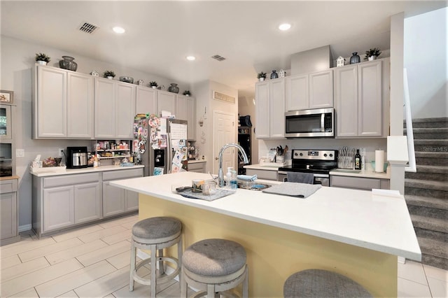 kitchen with stainless steel appliances, a kitchen bar, sink, and a center island with sink