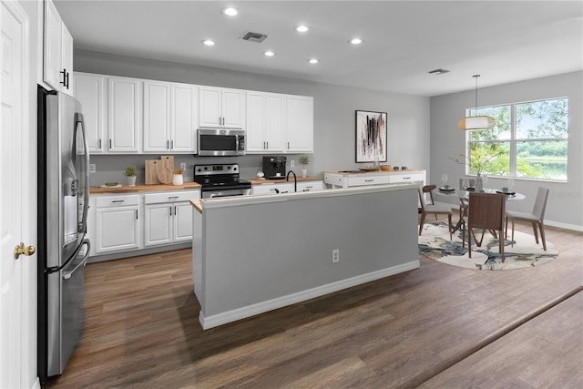 kitchen with dark hardwood / wood-style flooring, hanging light fixtures, stainless steel appliances, and white cabinets