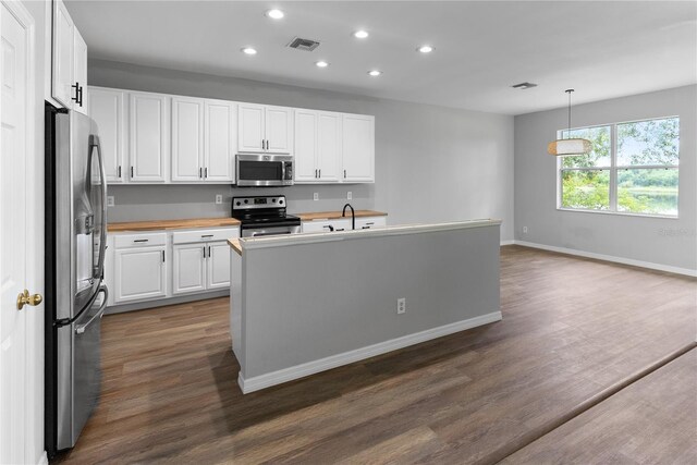 kitchen with appliances with stainless steel finishes, dark hardwood / wood-style floors, pendant lighting, and white cabinets