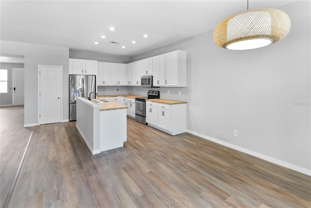 kitchen with pendant lighting, stainless steel appliances, hardwood / wood-style floors, and white cabinets