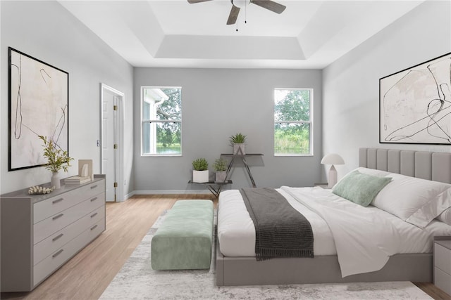 bedroom featuring ceiling fan, radiator heating unit, a raised ceiling, and light hardwood / wood-style flooring