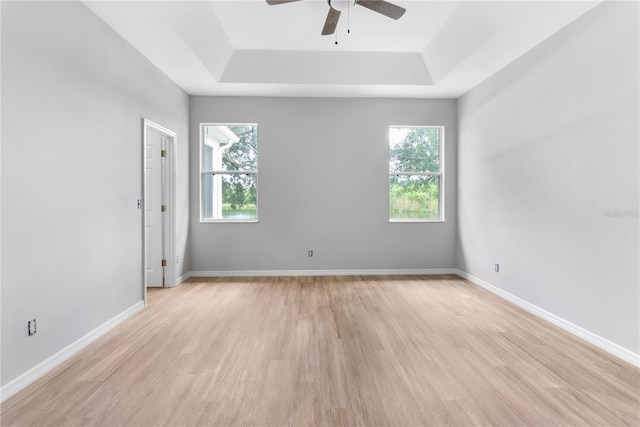 spare room featuring a tray ceiling, light hardwood / wood-style floors, and ceiling fan