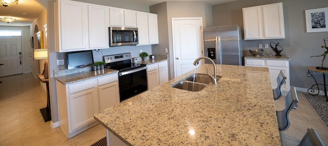 kitchen featuring sink, appliances with stainless steel finishes, light stone countertops, a kitchen island with sink, and white cabinets