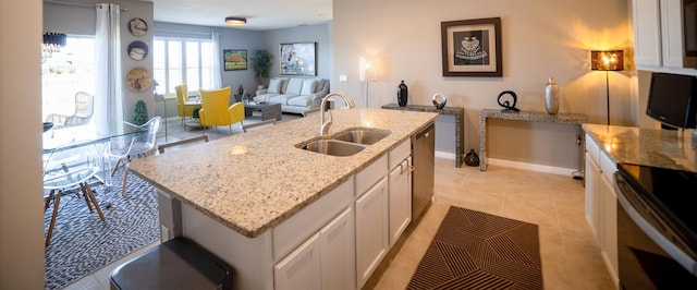 kitchen featuring sink, dishwasher, white cabinetry, light stone countertops, and an island with sink