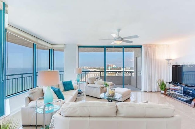 living room with a wall of windows, ceiling fan, and a water view