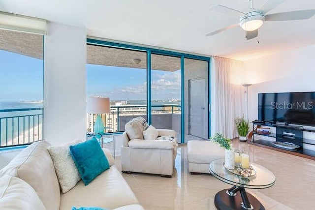 tiled living room featuring a water view, a wall of windows, and ceiling fan