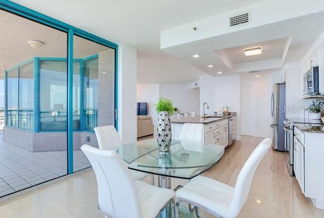 dining area featuring sink and a tray ceiling