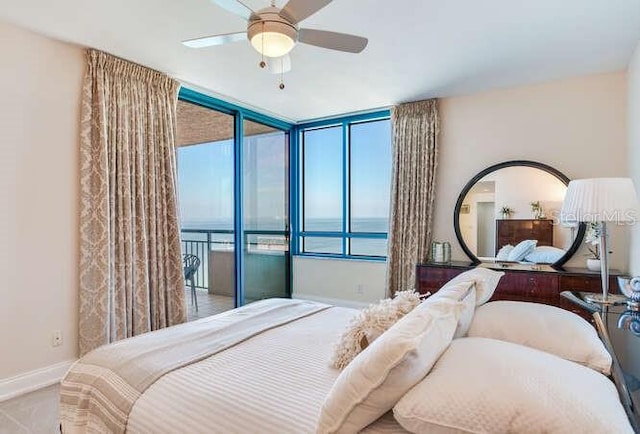 bedroom featuring a water view, ceiling fan, and a wall of windows