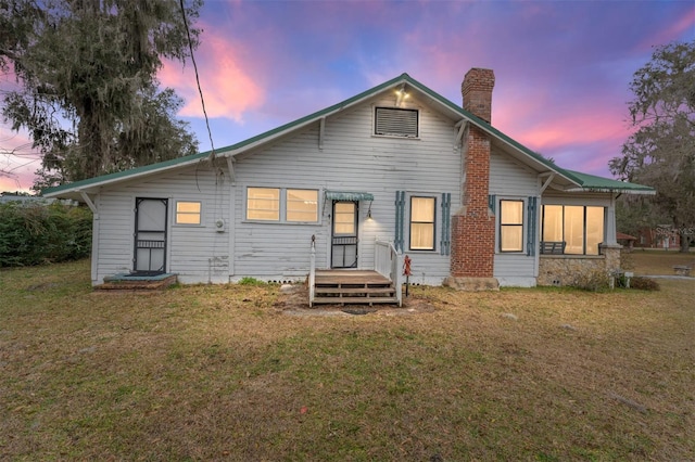 back house at dusk featuring a yard