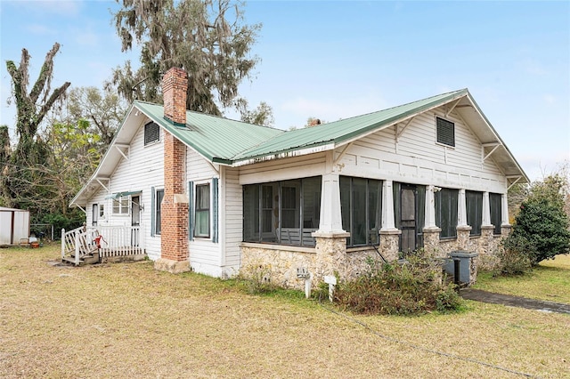 view of property exterior featuring a lawn and a sunroom