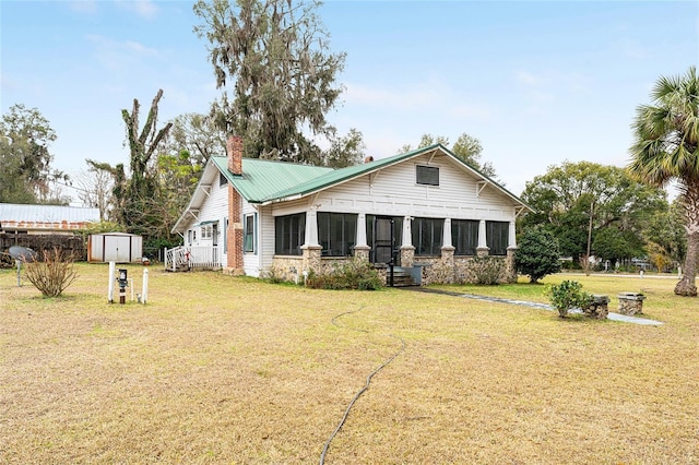 view of front of home featuring a storage shed, a front lawn, and a sunroom