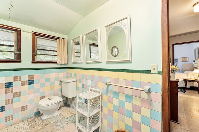 bathroom featuring tile walls, tile patterned floors, toilet, and lofted ceiling