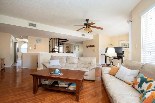 living room featuring ceiling fan, hardwood / wood-style floors, and a textured ceiling