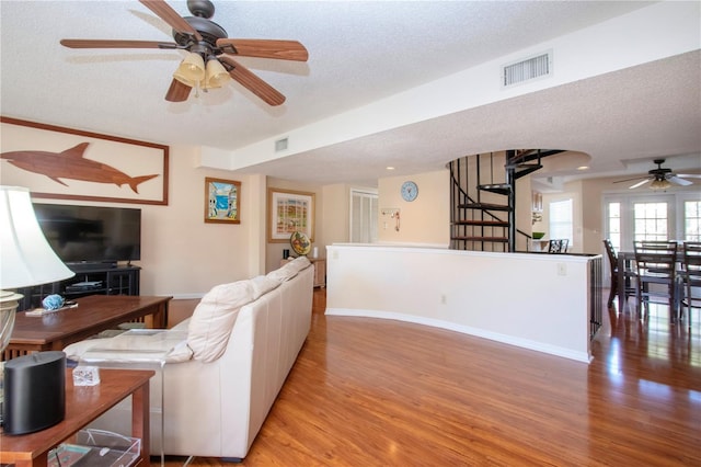 living room with ceiling fan, light hardwood / wood-style flooring, and a textured ceiling