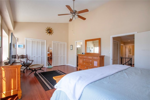 bedroom featuring dark hardwood / wood-style flooring, two closets, high vaulted ceiling, and ceiling fan