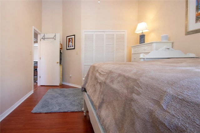 bedroom featuring a towering ceiling, dark wood-type flooring, and a closet