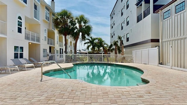 community pool with fence and a patio