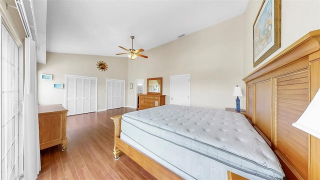 bedroom with multiple closets, wood finished floors, a ceiling fan, and high vaulted ceiling
