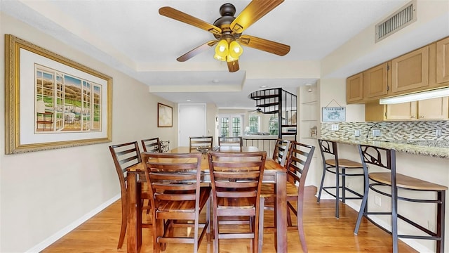 dining room with light wood finished floors, ceiling fan, and baseboards