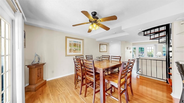 dining space featuring light wood-style floors, a ceiling fan, baseboards, a tray ceiling, and recessed lighting