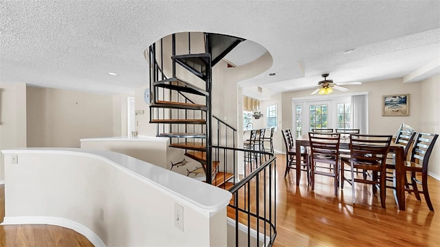 stairway featuring a textured ceiling, wood finished floors, baseboards, ceiling fan, and recessed lighting