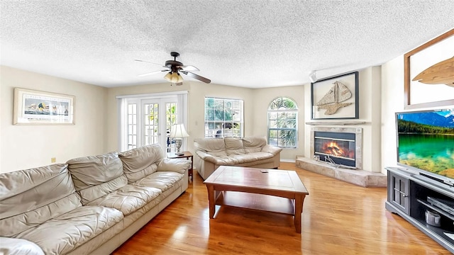 living room with light wood-style floors, ceiling fan, healthy amount of natural light, and a textured ceiling