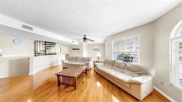 living room with wood finished floors, a textured ceiling, stairs, a ceiling fan, and baseboards