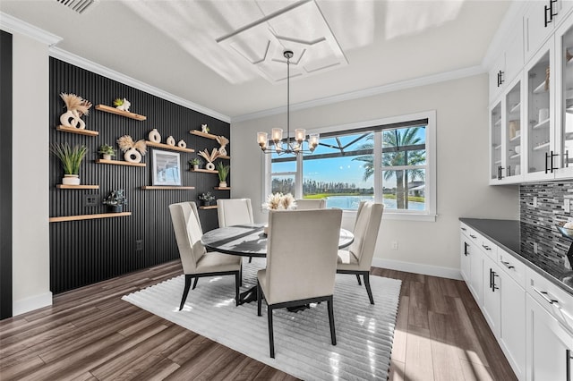 dining space with ornamental molding, a notable chandelier, and dark hardwood / wood-style flooring