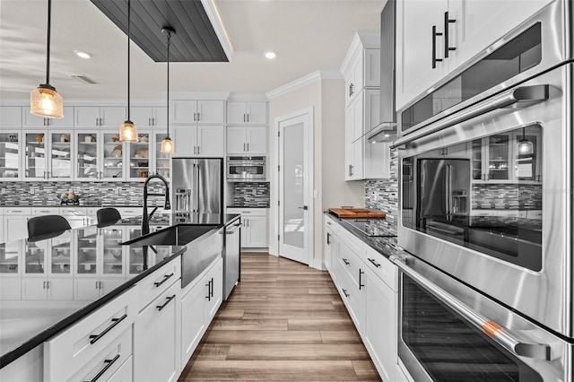 kitchen featuring pendant lighting, sink, hardwood / wood-style flooring, appliances with stainless steel finishes, and white cabinetry