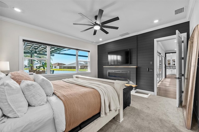 bedroom featuring wooden walls, carpet flooring, ornamental molding, and a fireplace