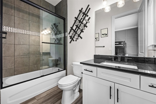 full bathroom featuring enclosed tub / shower combo, hardwood / wood-style floors, vanity, and toilet