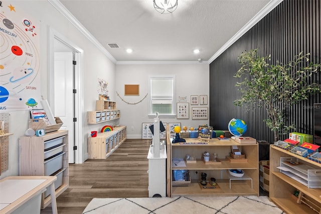 recreation room with ornamental molding and hardwood / wood-style floors