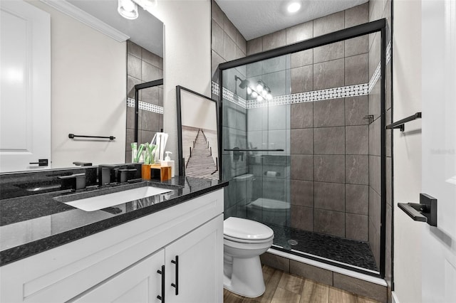 bathroom featuring a shower with door, vanity, ornamental molding, a textured ceiling, and toilet