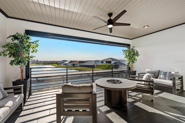 view of patio with a water view, an outdoor living space with a fire pit, and ceiling fan