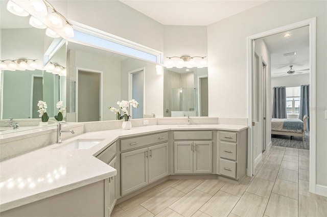 ensuite bathroom featuring ceiling fan, double vanity, an enclosed shower, and a sink