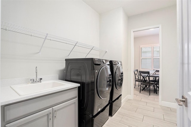 laundry area featuring washing machine and clothes dryer, baseboards, wood tiled floor, cabinet space, and a sink