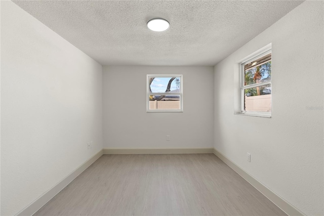 unfurnished room featuring a textured ceiling and light wood-type flooring