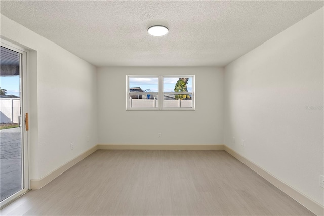 empty room with light hardwood / wood-style flooring and a textured ceiling