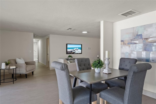 dining area featuring light hardwood / wood-style flooring and a textured ceiling