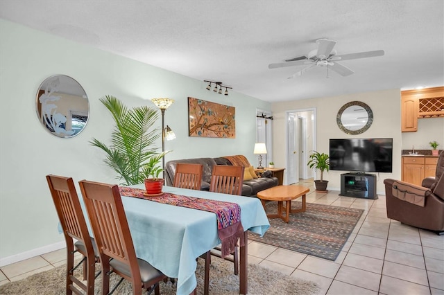 dining room with light tile patterned flooring, ceiling fan, sink, and a textured ceiling