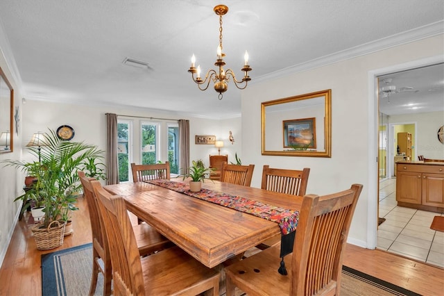 dining room featuring crown molding, a notable chandelier, and light hardwood / wood-style flooring