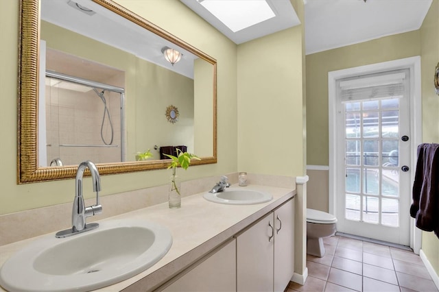 bathroom featuring tile patterned flooring, a skylight, vanity, a shower with shower door, and toilet