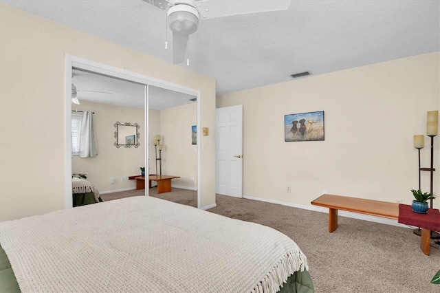 carpeted bedroom with ceiling fan, a closet, and a textured ceiling