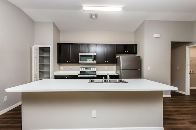 kitchen with a kitchen island with sink, sink, dark hardwood / wood-style flooring, and appliances with stainless steel finishes