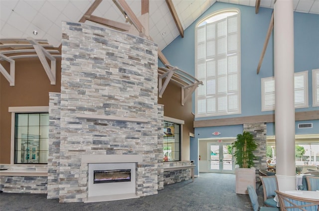 unfurnished living room featuring carpet floors, a large fireplace, high vaulted ceiling, and french doors