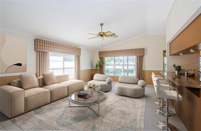 living room with vaulted ceiling, ornamental molding, a wealth of natural light, and light tile patterned floors